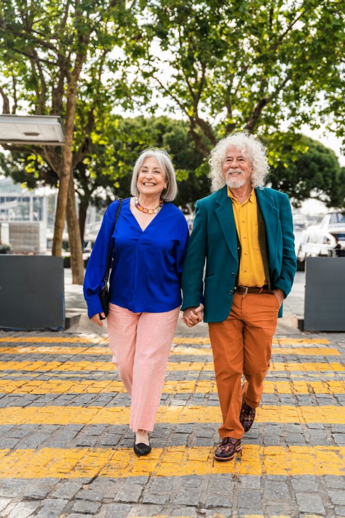 Elderly couple holding hands while walking outdoors, symbolizing lasting relationships and health.